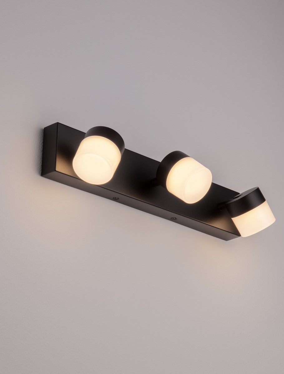 Kinkiet Nueva 3xLED 17W w kolorze czarnym, montowany na ścianie, z trzema okrągłymi kloszami z białego tworzywa. Ujęcie frontalne, pokazujące równomierne rozmieszczenie źródeł światła na prostokątnej podstawie.