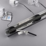 Lampa wisząca Rika 3xLED 18W w kolorze czarnym dymionym. Widoczna metalowa konstrukcja z okablowaniem, w tym zasilacz. Elementy lampy zapakowane w folie ochronne. Tło w odcieniu szarości.