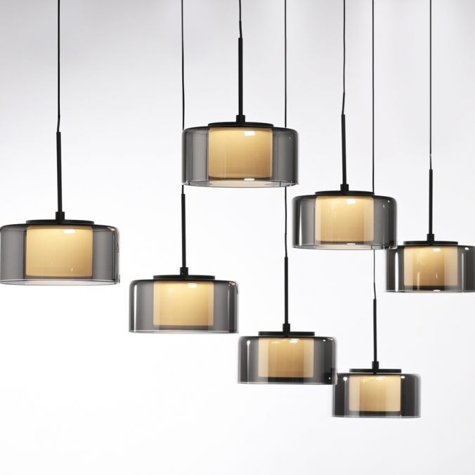 Lampa wisząca Rika z 7 źródłami LED, o mocy 56W, w czarnych, dymionych kloszach. Klosze mają okrągły kształt i są zawieszone na cienkich przewodach w różnych wysokościach, co tworzy dynamiczny efekt wizualny.