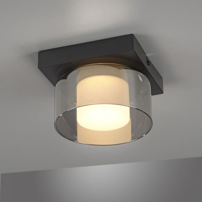 Lampa sufitowa LED Rika o mocy 4,5W, czarna, z dymionym kloszem. Okrągły, przezroczysty klosz otacza białą żarówkę, zamontowana na kwadratowej, matowej podstawie. Produkt montowany na suficie, idealny do nowoczesnych wnętrz.