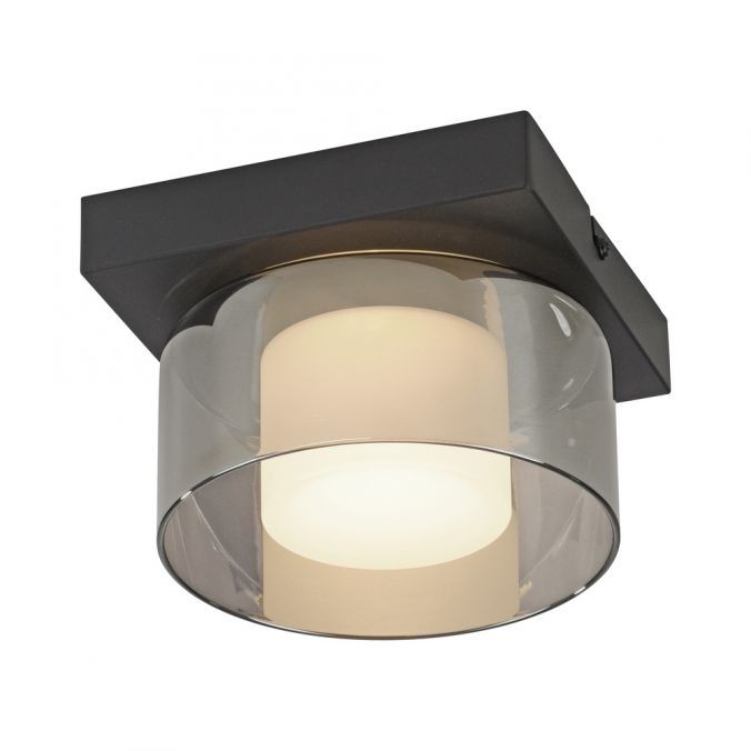 Lampa sufitowa LED Rika 4,5W w czarnym, dymionym kloszu. Prosta, kwadratowa podstawa z metalu, przezroczysty klosz z białym źródłem światła w środku. Idealna do nowoczesnych wnętrz, zamontowana na suficie.