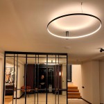Czarna lampa sufitowa LED Ring D90 o mocy 50W, w kształcie okręgu, zawieszona na suficie. Emituje ciepłe światło, widoczna w nowoczesnym wnętrzu z drewnianymi schodami i przeszklonymi ścianami.