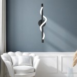Meleca kinkiet LED 12W CCT w kolorze czarnym, zamontowany na ścianie, z falującą, białą oprawą. W tle widoczny jasny fotel w stylu skandynawskim oraz szare ściany, co podkreśla nowoczesny design lampy.
