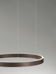 Brązowa lampa wisząca Bari D60 z jedno źródło LED 60W, o okrągłym, matowym kształcie. Zawieszona na cienkich linkach, emituje delikatne światło z krawędzi, idealna do nowoczesnych wnętrz. Tło w jasnym odcieniu podkreśla jej elegancki design.