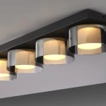 Czarna lampa sufitowa Rika z czterema źródłami światła LED, każdy z przezroczystym, dymionym kloszem. Produkt zamontowany na prostokątnej podstawie, z delikatnym, ciepłym światłem. Idealna do nowoczesnych wnętrz.