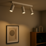 Lampa sufitowa Mica (spot) z trzema oprawami GU10 w kolorze białym i chromowanym, zamontowana na prostokątnej podstawie. Ujęcie z dołu, ukazujące kierunek światła oraz subtelne oświetlenie ściany z grafiką i meblami w tle.