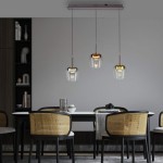 Lampa wisząca Q-kon z pilotem, 3 klosze w różnych kolorach, zawieszone na cienkich linkach. Wyróżniają się szklanym wykończeniem i metalowymi detalami. Umieszczona nad stołem w nowoczesnej aranżacji, na tle jasnej ściany.
