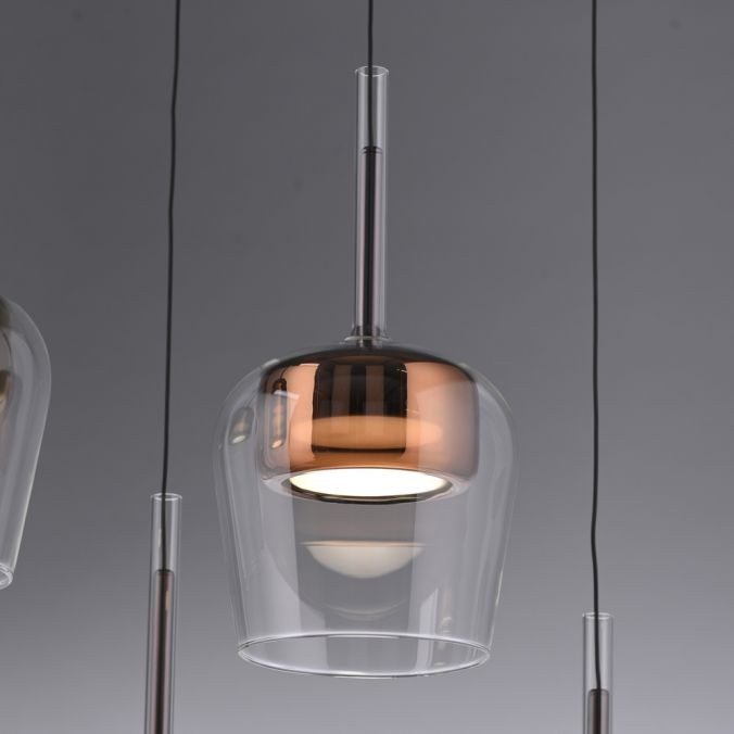 Lampa wisząca Q-kon z pilotem LED 9W CCT, w kolorze miedzi. Szklany klosz o zaokrąglonym kształcie z metalicznym wykończeniem. Zawieszona na cienkich przewodach, z widocznym źródłem światła wewnątrz. Idealna do nowoczesnych wnętrz.