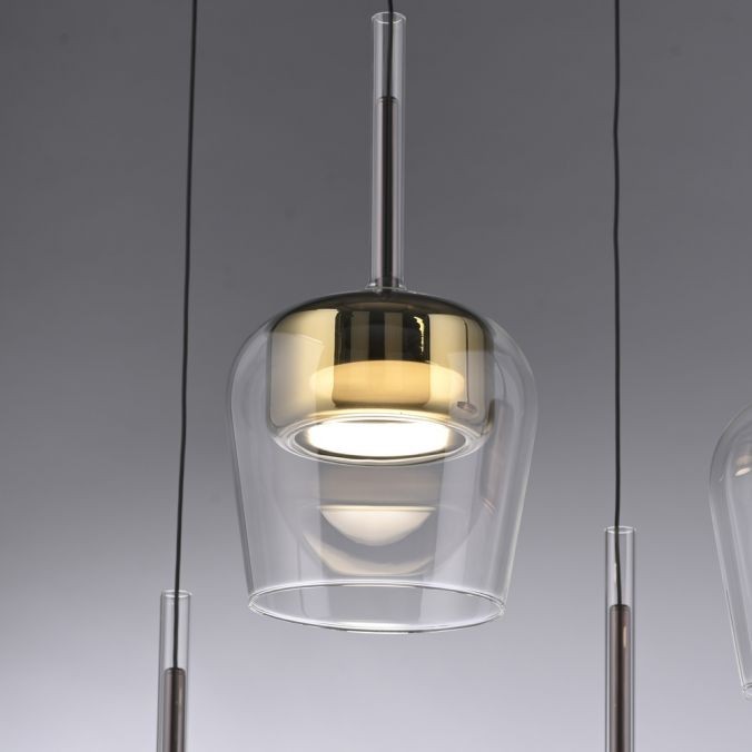 Lampa wisząca Q-kon z pilotem, LED 9W, w kolorze złotym. Szklany klosz o opływowym kształcie, zawieszony na przezroczystym przewodzie. Światło emitowane jest w dół, a podstawa ma połyskujące wykończenie.