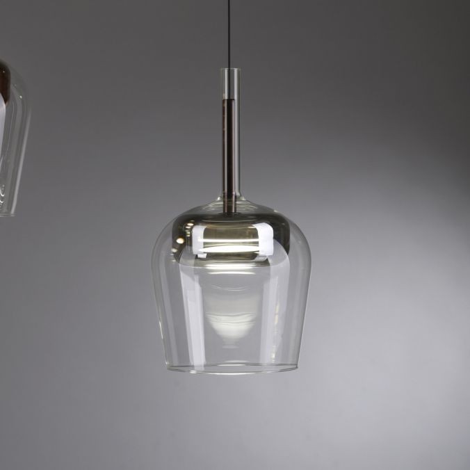Lampa wisząca Q-kon z pilotem LED 9W CCT w srebrnym kolorze, o szklanej, przezroczystej obudowie w kształcie dzwonu. Zawieszona na cienkim przewodzie, przedstawiona z boku, w minimalistycznym otoczeniu.
