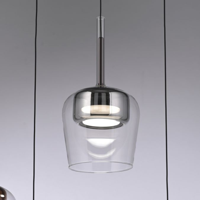 Lampa wisząca Q-kon w kolorze srebrnym, wykonana z przezroczystego szkła, z okrągłym źródłem światła LED 9W CCT. Zawieszona na cienkim przewodzie, z widocznym pilotem do sterowania. Kąt ujęcia frontalny.
