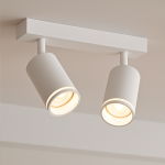 Lampa sufitowa Pipe Ring w kolorze białym z dwoma reflektorami GU10. Reflektory mają okrągły kształt i są zamontowane na prostokątnej podstawie. Ujęcie z dołu, ukazujące detale strukturalne i źródła światła.