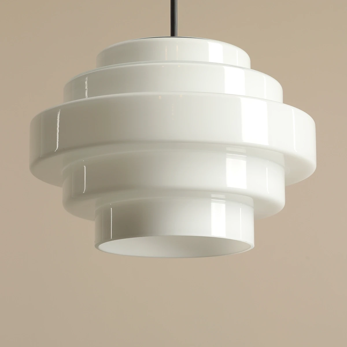 Lampa wisząca Filo w stylu retro, czarna, o średnicy 22 cm i wysokości 104 cm. Ma charakterystyczny, warstwowy kształt z matowego materiału. Zawieszona na cienkim przewodzie, idealna do nowoczesnych wnętrz.