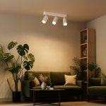 Lampa sufitowa Pipe Ring z trzema reflektorami GU10 w kolorze białym, zamontowana na prostokątnej podstawie. Reflektory są ustawione w linii, skierowane w różnych kierunkach. Lampa znajduje się w jasnym wnętrzu z zieloną sofą i roślinami.