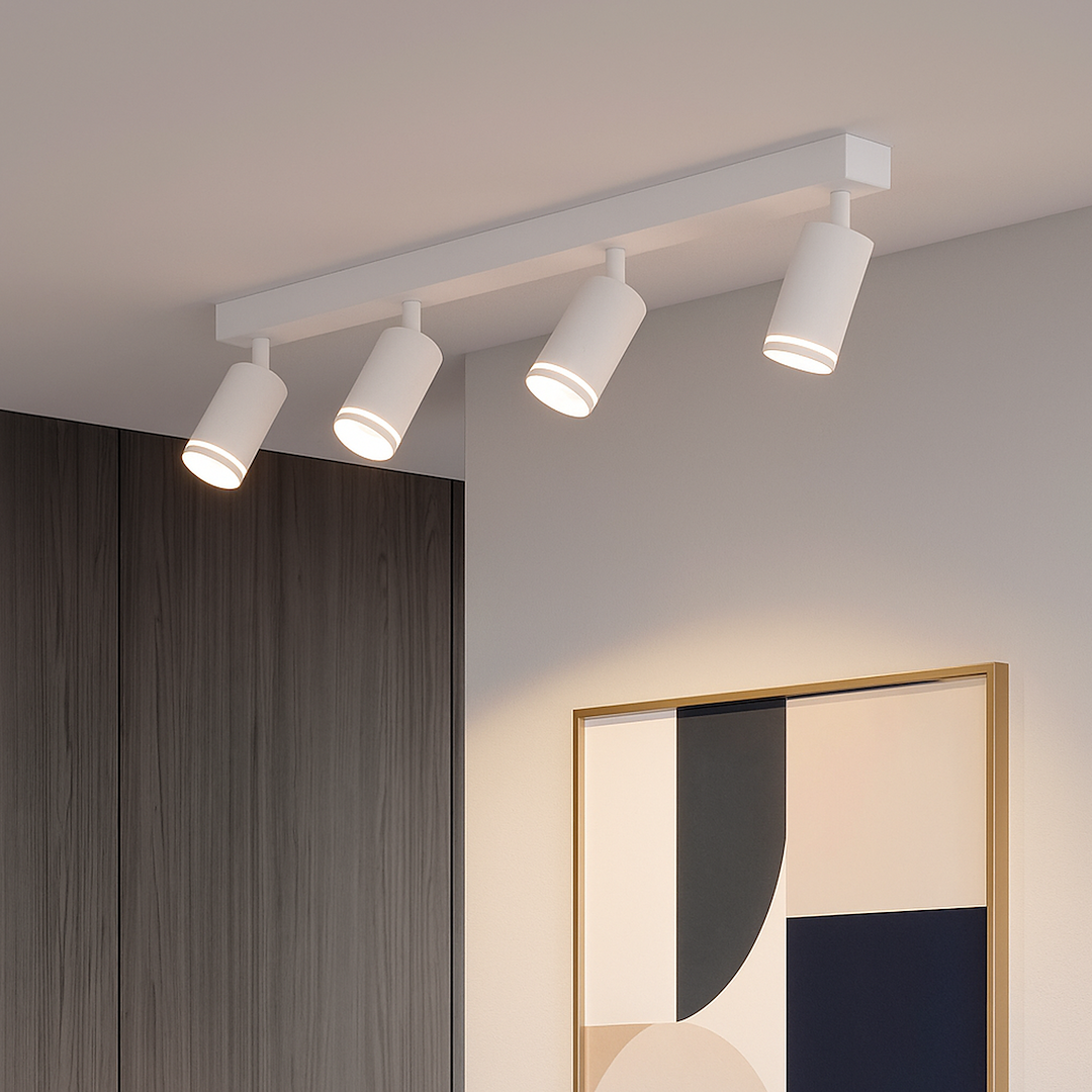 Lampa sufitowa Pipe Ring z czterema reflektorami GU10 w kolorze białym. Ułożona równolegle na suficie, z wyraźnym, minimalistycznym designem. W tle widoczna część ściany z drewnianymi panelami oraz obraz w ramie.