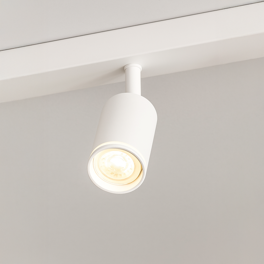 Biała lampa sufitowa typu spot z jednym źródłem światła GU10, zamocowana na prostym uchwycie. Cylindryczny kształt z zaokrąglonym końcem, umieszczona na jasnym tle. Idealna do oświetlenia wnętrz.