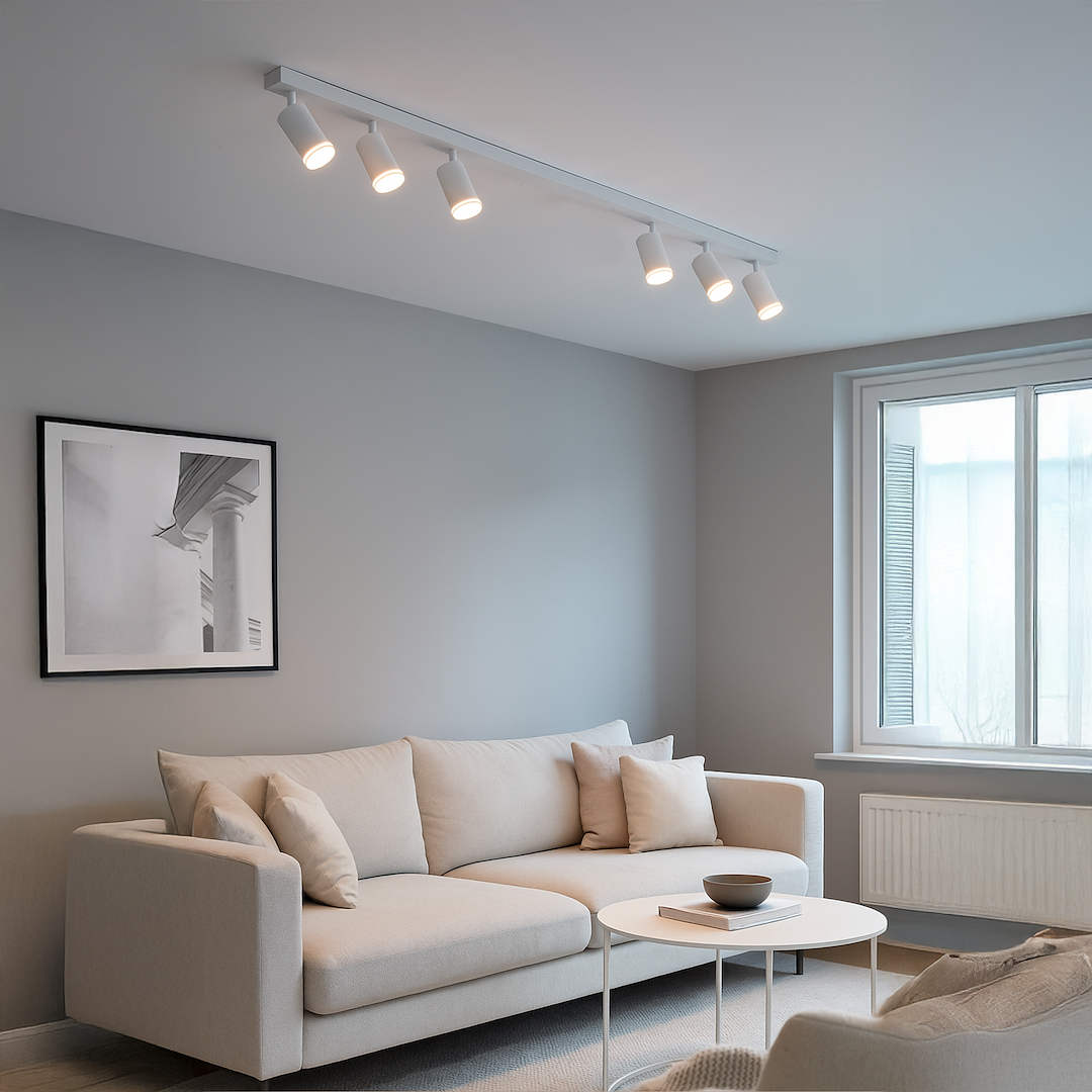 Lampa sufitowa Pipe Ring z sześcioma białymi spotami GU10, zamontowana na prostym, metalowym wsporniku. Widoczna w nowoczesnym wnętrzu obok jasnej kanapy i stołu kawowego. Światło kierowane na ścianę z czarno-białym obrazem.