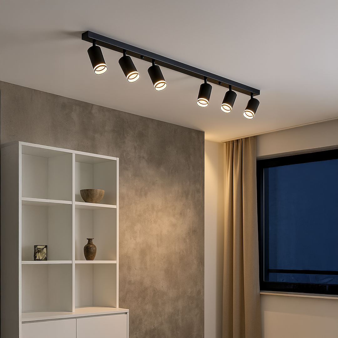 Lampa sufitowa Pipe Ring w kolorze czarnym z sześcioma reflektorami GU10. Zainstalowana na prostokątnej listwie, z widocznym, matowym wykończeniem. Ujęcie z boku w nowoczesnym wnętrzu z szafką i oknem.