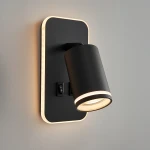 Kinkiet Pipe Ring w kolorze czarnym z okrągłą oprawą, na ścianie z wbudowanym LED 6W. Ujęcie z boku, lampa skierowana na dół, z widocznym przełącznikiem. Tło jednolite, neutralne.