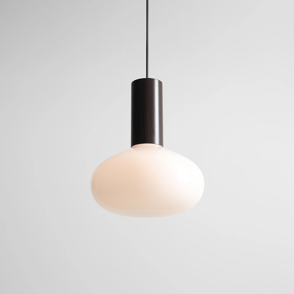Lampa wisząca Flo Mokka D26 z kloszem w kształcie owalnym w kolorze matowej bieli oraz czarnym, cylindrycznym uchwytem. Zawieszona na cienkim kablu, prezentująca nowoczesny design. Idealna do wnętrz minimalistycznych.