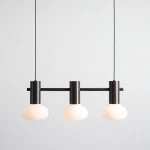 Lampa wisząca Flo Mokka z trzema oprawkami E14, w kolorze ciemnego brązu. Posiada okrągłe, mleczne klosze, zawieszona na cienkim przewodzie. Prosty, nowoczesny design idealny do różnych wnętrz.