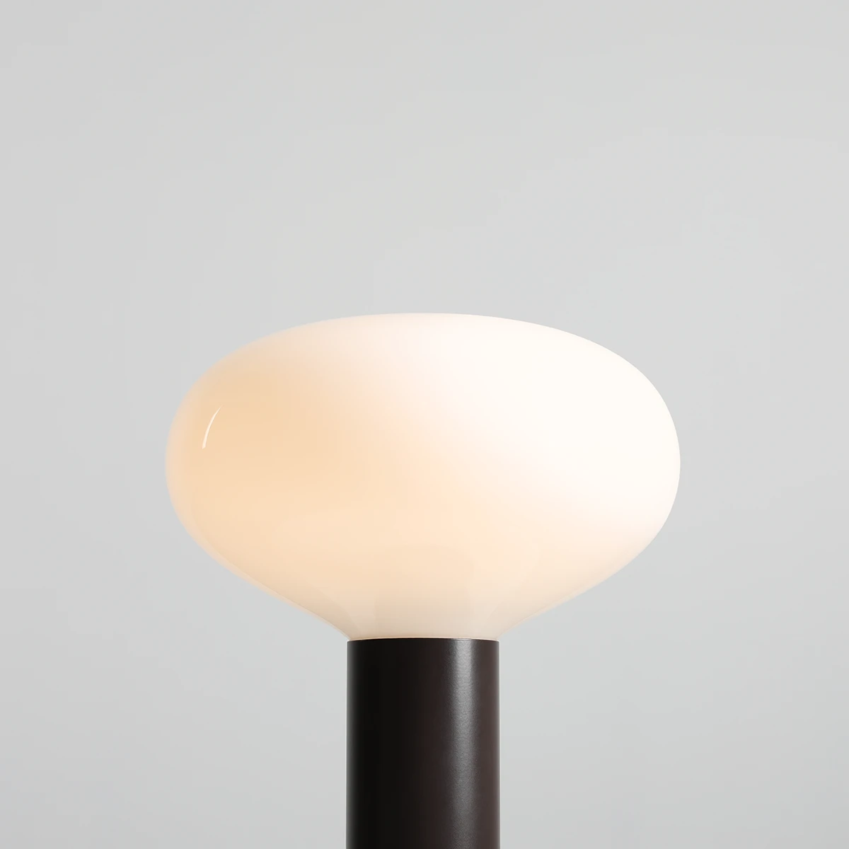 Duża lampa stołowa Flo Mokka z kloszem w kształcie owalnej misy w kolorze białym, umieszczona na ciemnej, metalowej podstawie. Widok z góry, ukazujący gładką powierzchnię klosza i elegancki design.