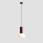 Lampa wisząca Flo Ruby D19 z żarnikiem E14, o cylindrycznym, bordowym korpusie i okrągłej, mlecznobiałej kloszu. Zawieszona na cienkim, czarnym przewodzie, prezentuje minimalistyczny design na szarym tle.