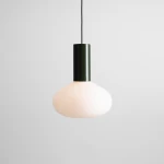 Lampa wisząca Flo Moss D26 z oprawą w kolorze ciemnozielonym i mlecznobiałym kloszem w kształcie kulistym. Zawieszona na cienkim przewodzie, prezentuje nowoczesny design. Idealna do wnętrz w stylu minimalistycznym.