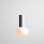 Lampa wisząca Flo Grey D19 z oprawą w kolorze szarym i kloszem w kształcie kuli, wykonanym z mlecznego szkła, zawieszona na cienkim przewodzie. Klosz ma delikatnie zaokrąglony kształt, co nadaje mu nowoczesny charakter.