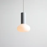 Lampa wisząca Flo Grey D19 z metalowym, szarym trzonem i kulistym kloszem z mlecznego szkła. Ujęcie frontalne, zawieszona na cienkim przewodzie, na jasnym tle. Przeznaczona do żarówki E14.