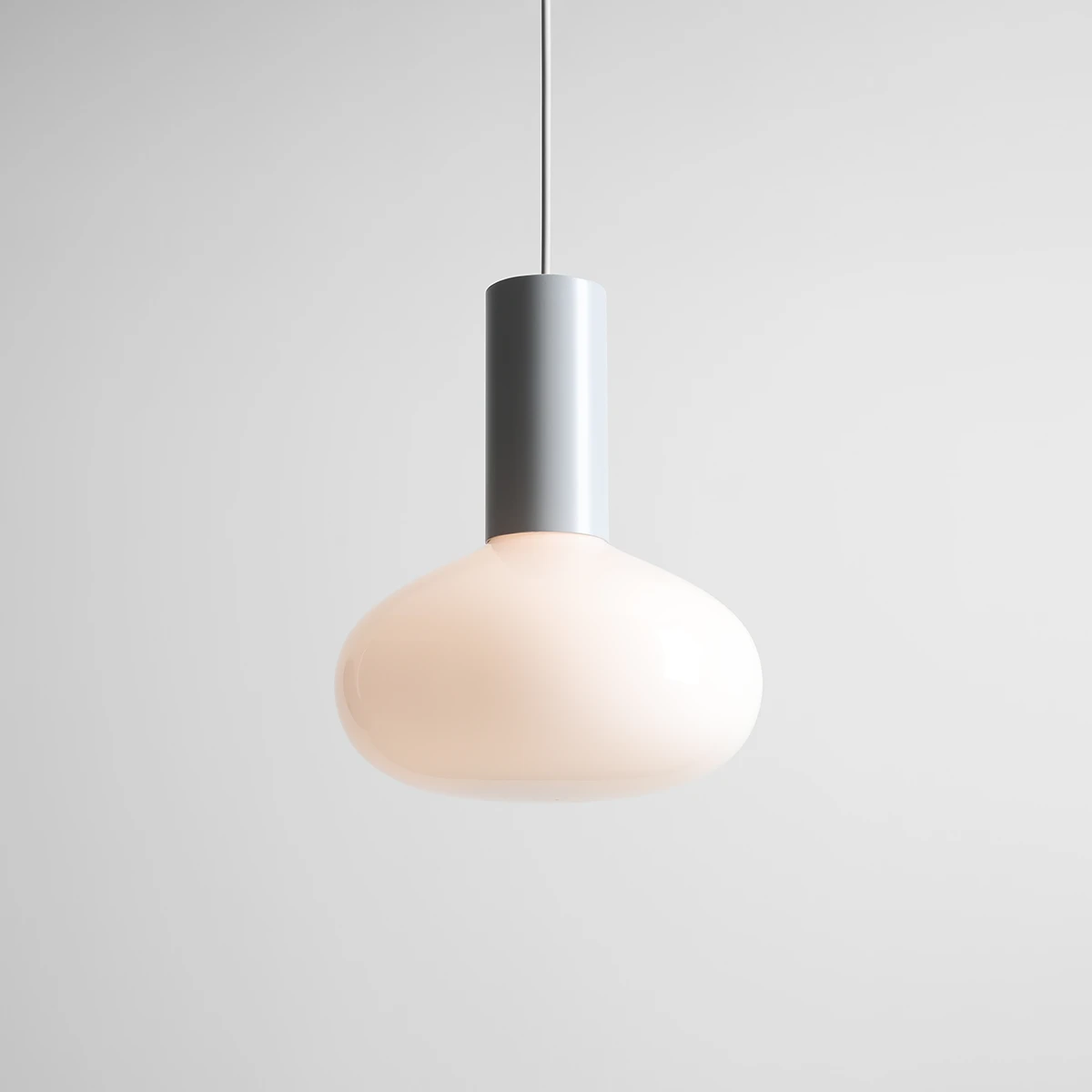 Lampa wisząca Flo Grey D26 z metalowym, szarym trzonkiem i kulistym, mlecznym kloszem. Produkt zawieszony na cienkim przewodzie, z minimalistycznym designem, na jednolitym, jasnym tle.