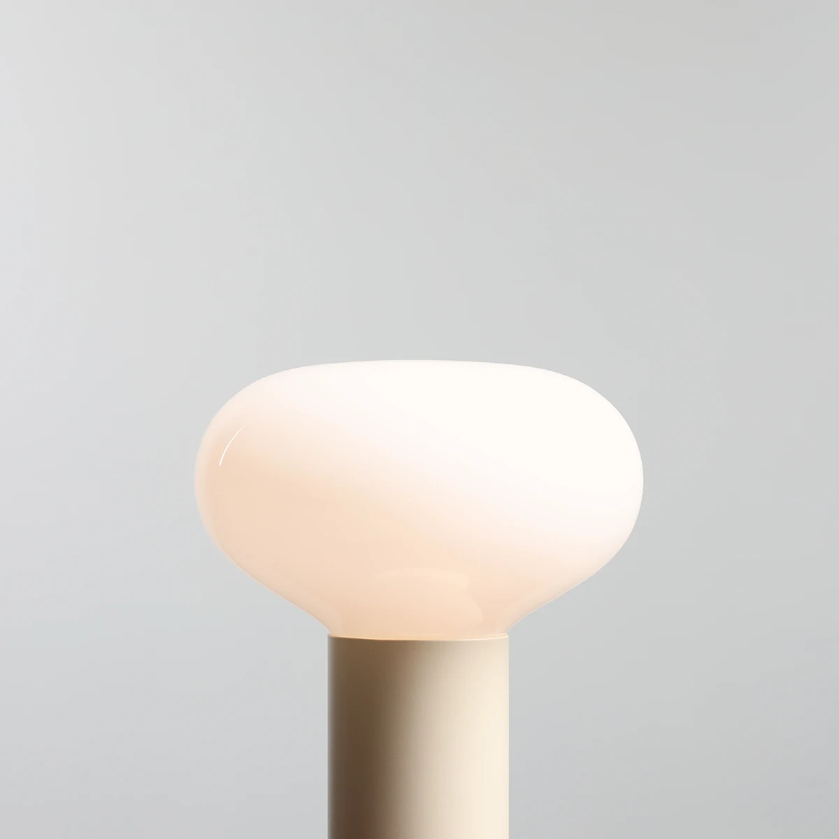 Lampa stołowa Flo Cream z okrągłą, mlecznobiałą głowicą i jasnobeżową podstawą. Ujęcie z góry, pokazujące gładką, zaokrągloną formę klosza. Prosty, nowoczesny design, idealna do wnętrz.