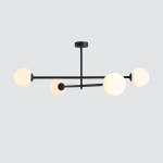 Czarna lampa sufitowa Pinne z czterema kulistymi kloszami w kolorze mlecznym, zawieszona na cienkim, prostym stelażu. Ujęcie frontalne, ukazujące równomierne rozmieszczenie elementów. Idealna do nowoczesnych wnętrz.