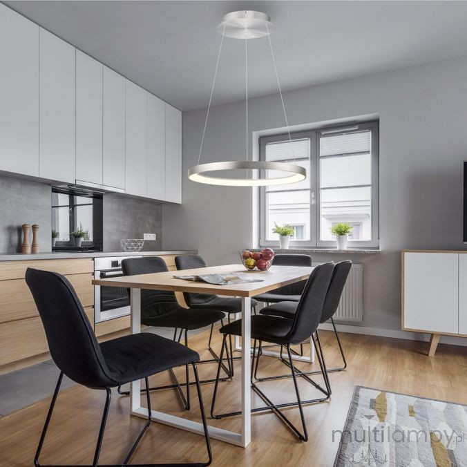 Lampa wisząca LED Hoop koło 37W 3000K w kolorze aluminium, zawieszona nad drewnianym stołem w nowoczesnej kuchni. W tle widoczne czarne krzesła i okno z roślinami. Oświetlenie daje ciepłe światło, podkreślając minimalistyczny design wnętrza.