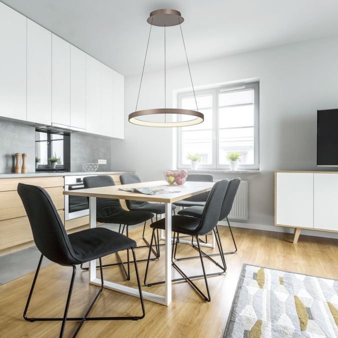 Lampa wisząca LED Hoop o mocy 37W i barwie 3000K w kolorze kawowym, zawieszona nad stołem w nowoczesnej kuchni. Prosta, okrągła forma z metalowym wykończeniem. W tle widoczne czarne krzesła i jasne meble.