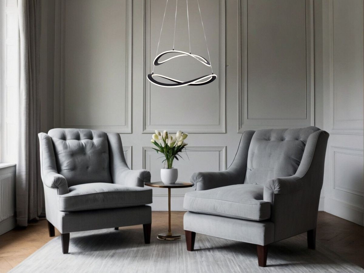 Lampa wisząca Jauja 2xLED 87W w kolorze czarnym, o nowoczesnym kształcie, zawieszona nad stolikiem, w otoczeniu dwóch szarych foteli i kwiatów w doniczce. Tło w jasnych odcieniach, z elegancką aranżacją wnętrza.