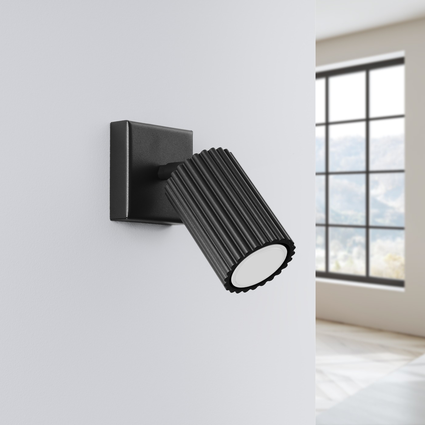 Kinkiet Karbon 1xGU10 w kolorze czarnym, zamontowany na ścianie, z okrągłym kloszem w żłobieniach. Ujęcie z boku, pokazujące jego minimalistyczny design i teksturę. Tło jasne, z widokiem na okno w tle.