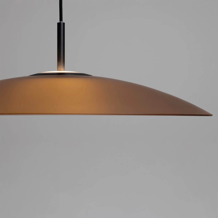 Lampa wisząca Peca z jedną diodą LED 17W, o czarnej metalowej podstawie i brązowym kloszu w kształcie płaskiej, szerokiej czaszy. Produkt zawieszony na cienkim przewodzie, w tle neutralna szara ściana.