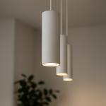 Lampa wisząca Track Pipe 1xGU10 w kolorze białym, o cylindrycznym kształcie, zawieszona na białym kablu. Widoczna elegancka oprawa z delikatnym światłem, z tłem w jasnym wnętrzu i rośliną w dolnym rogu.