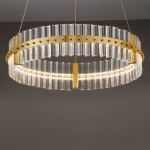 Lampa wisząca Mayo D60 z jednym źródłem LED 45W, w złotej oprawie. Okrągła konstrukcja z przezroczystymi, prostokątnymi elementami szklanymi oraz złotymi detalami. Zawieszona na cienkich linkach, idealna do nowoczesnych wnętrz.