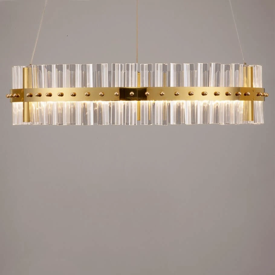 Lampa wisząca Mayo D60 w kolorze złotym z przezroczystymi, prostokątnymi elementami. Posiada jeden źródło światła LED o mocy 45W. Zawieszona na cienkich linkach, ma nowoczesny design z dekoracyjnymi kulkami na metalowej obręczy.