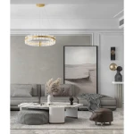 Lampa wisząca Mayo D78 w kolorze złotym, z 1 źródłem LED o mocy 56W. Okrągła konstrukcja z przezroczystymi elementami, zawieszona na cienkich linkach, w nowoczesnym wnętrzu z szarym kanapą i dekoracjami.