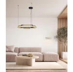 Lampa wisząca Roca 6xLED/39W w kolorze czarnym i złotym, o nowoczesnym kształcie, zawieszona na cienkich linkach. Umieszczona w minimalistycznym wnętrzu z jasnymi ścianami, szaro-beżową kanapą i drewnianymi akcentami.