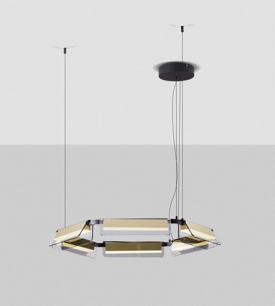 Lampa wisząca Roca z sześcioma diodami LED, o mocy 39W, w kolorze czarnym i złotym. Posiada nowoczesny, prostokątny kształt z przezroczystymi panelami. Montowana na długich przewodach, zawieszona na suficie, na jasnym tle.
