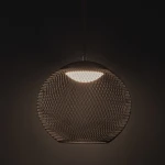 Czarna lampa wisząca Rita z metalową siatką, z oświetleniem LED 12W. Kształt okrągły, zawieszona pod sufitem. Emituje światło przez górną część klosza, w przestrzeni o ciemnym tle. Idealna do nowoczesnych wnętrz.