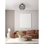 Czarna lampa sufitowa Rita z siatkowym kloszem, z jednym źródłem światła LED o mocy 19W. Zawieszona na suficie w nowoczesnym wnętrzu, na tle jasnej ściany i brązowej kanapy.