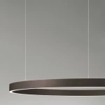 Brązowa lampa wisząca Bari D98 z jedną diodą LED 106W, w kształcie minimalistycznego okręgu, zawieszona na cienkich linkach. Oświetlenie emituje delikatne światło przez wąski pasek na krawędzi. Tło jasnoszare.
