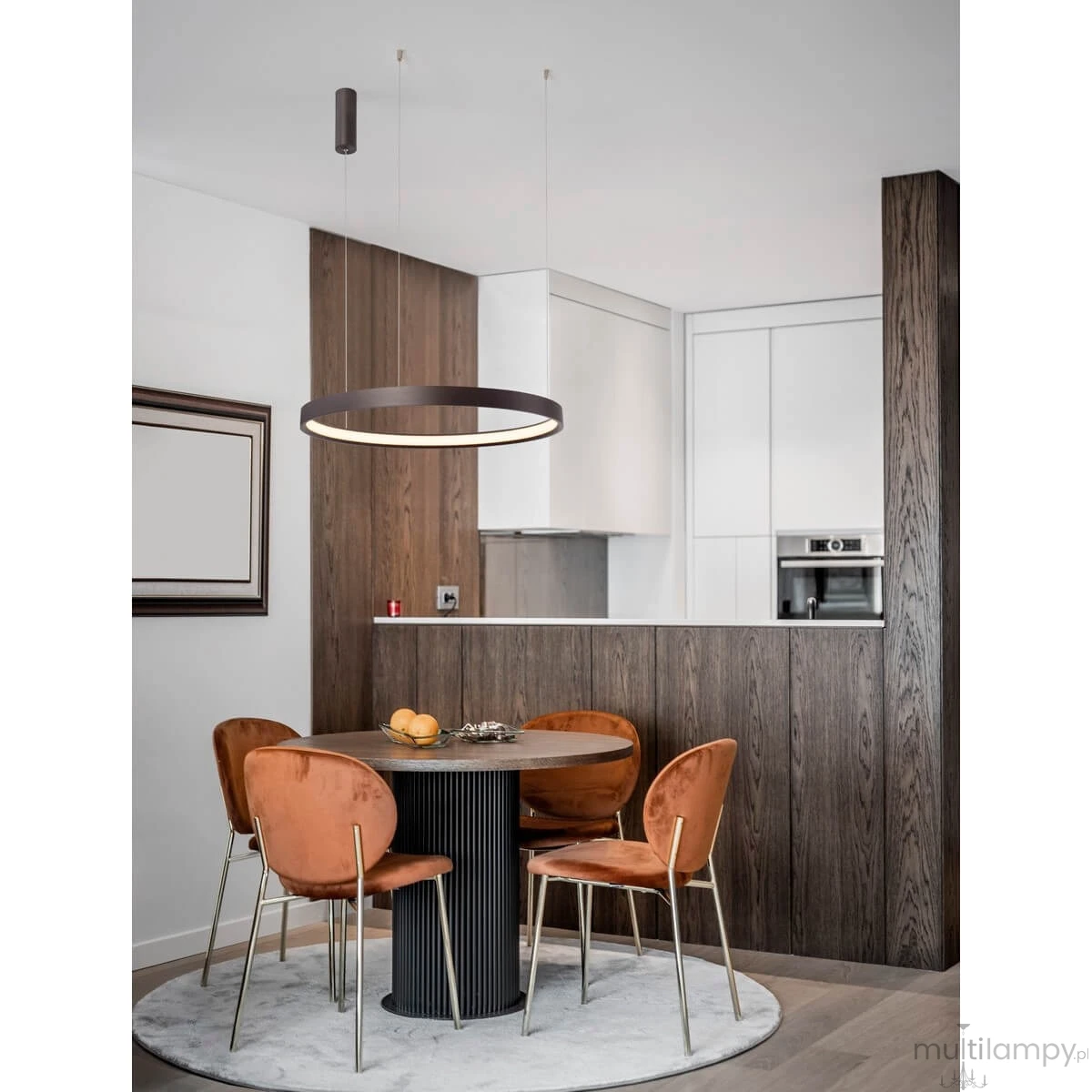 Brązowa lampa wisząca Zacapu D60 z jednym źródłem LED 40W, zawieszona nad okrągłym stołem. Okrągły kształt z cienką ramą i podświetleniem. W tle nowoczesna kuchnia z drewnianą zabudową i stylowymi krzesłami.
