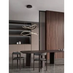 Lampa wisząca Jauja 2xLED 87W w kolorze czarnym, z dwoma falistymi, podświetlonymi elementami. Zawieszona na cienkich linkach, umieszczona w nowoczesnym wnętrzu z drewnianymi akcentami. Oświetlenie w centralnej części stołu.