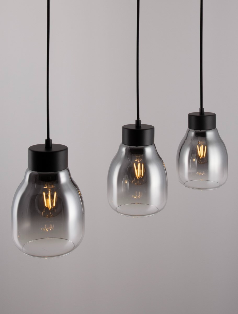 Lampa wisząca Moche w kolorze czarnym z trzema kloszami w kształcie szklanych pojemników. Każdy klosz zawiera żarówkę E27. Zawieszona na czarnych linkach, minimalistyczny design, idealna do nowoczesnych wnętrz. Tło jasne, jednolite.
